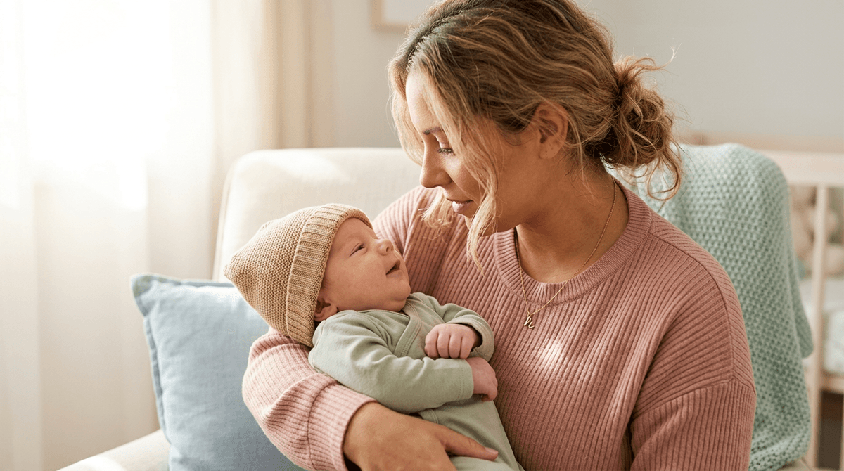Une mère tenant tendrement son bébé dans ses bras, créant un lien d'attachement sécure.
